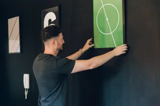 Andy straightens a football print on the walls at MadeByShape